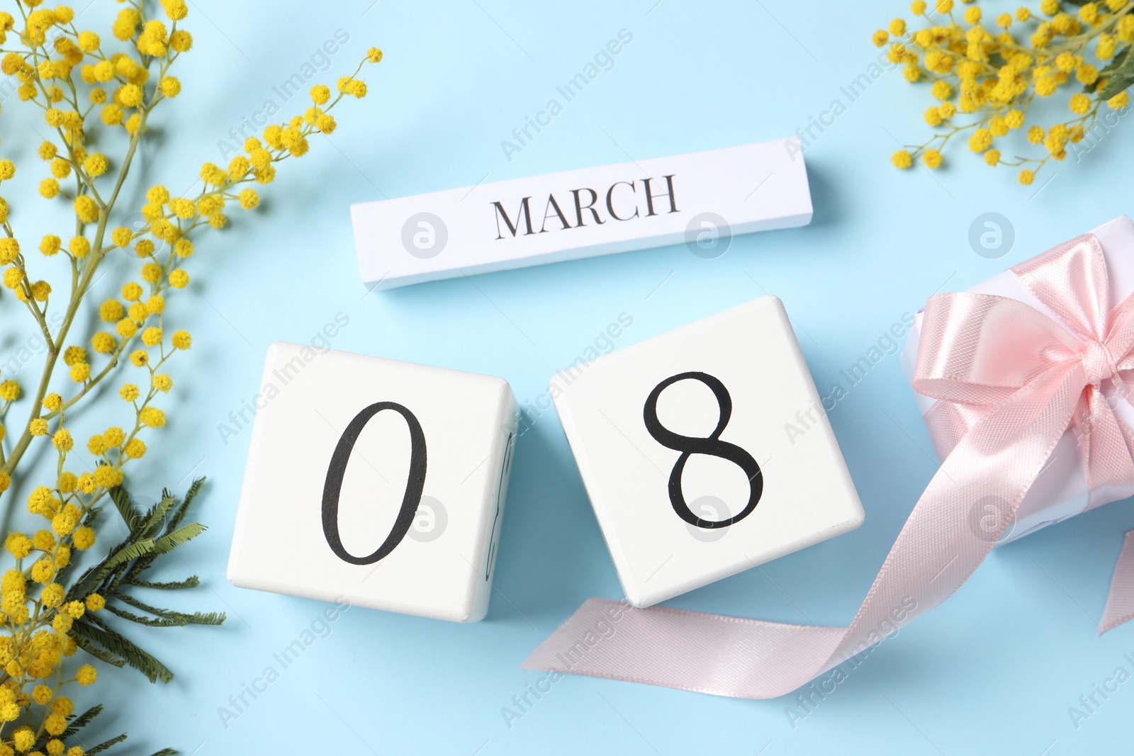 Photo of International Women's day - 8th of March. Gift box, wooden block calendar and beautiful flowers on light blue background, flat lay