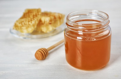 Photo of Jar of honey and dipper on table