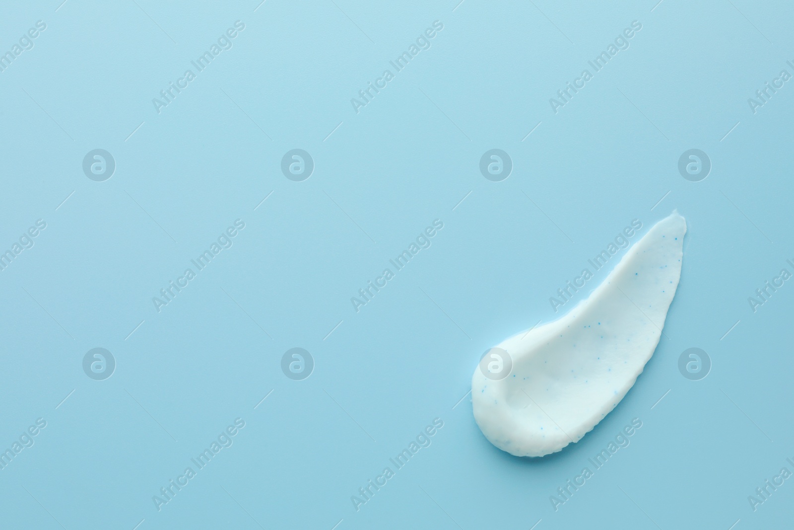 Photo of Sample of face scrub on light blue background, top view. Space for text