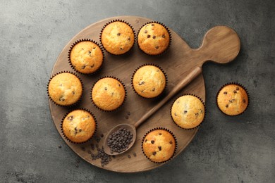 Delicious freshly baked muffins with chocolate chips on gray table, top view