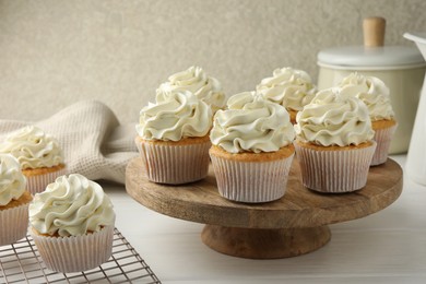 Tasty vanilla cupcakes with cream on white wooden table