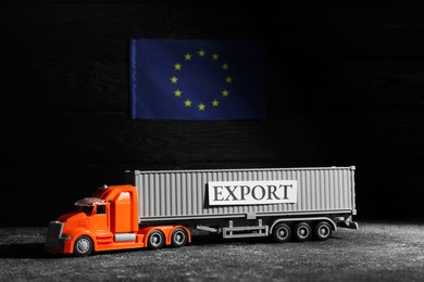 Toy truck and Europe flag on black background. Export concept