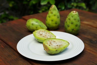 Photo of Tasty prickly pear fruits on wooden table outdoors