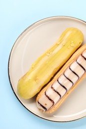 Photo of Delicious eclairs covered with glaze on light blue background, top view