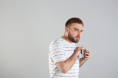Photo of Greedy young man hiding wallet with money on light grey background, space for text