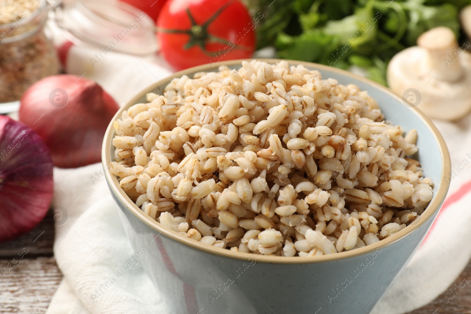 Photo of Delicious pearl barley in bowl on table, closeup