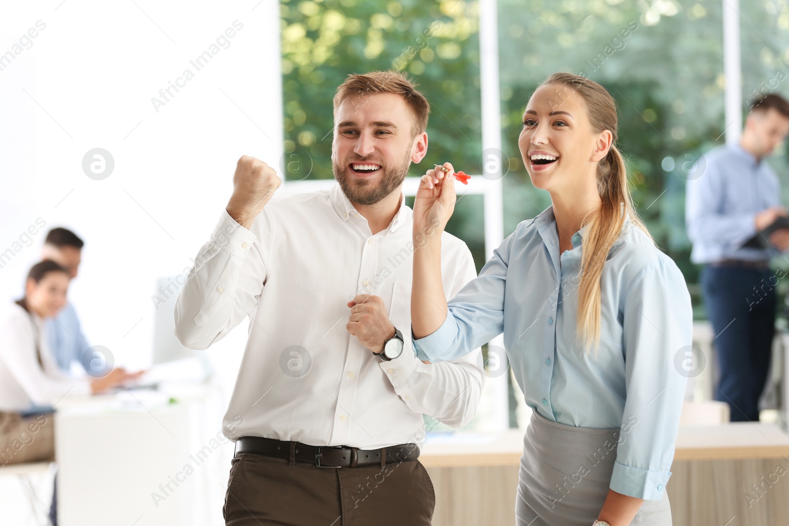 Photo of Happy young employees with dart in office