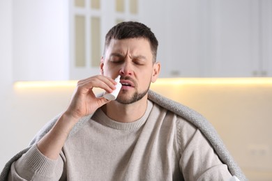Photo of Ill man using nasal spray at home