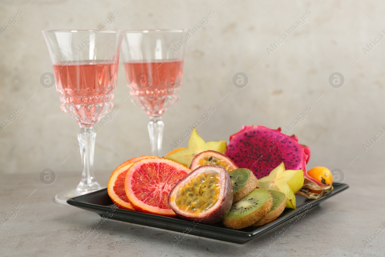 Photo of Delicious exotic fruits and wine on grey table