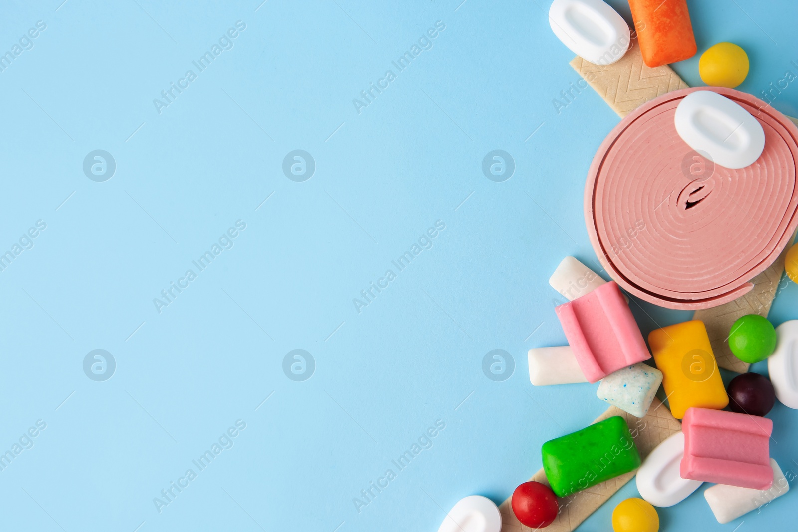 Photo of Many different chewing gums on light blue background, flat lay. Space for text