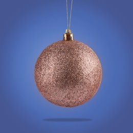 Image of Beautiful glittery Christmas ball hanging on blue background