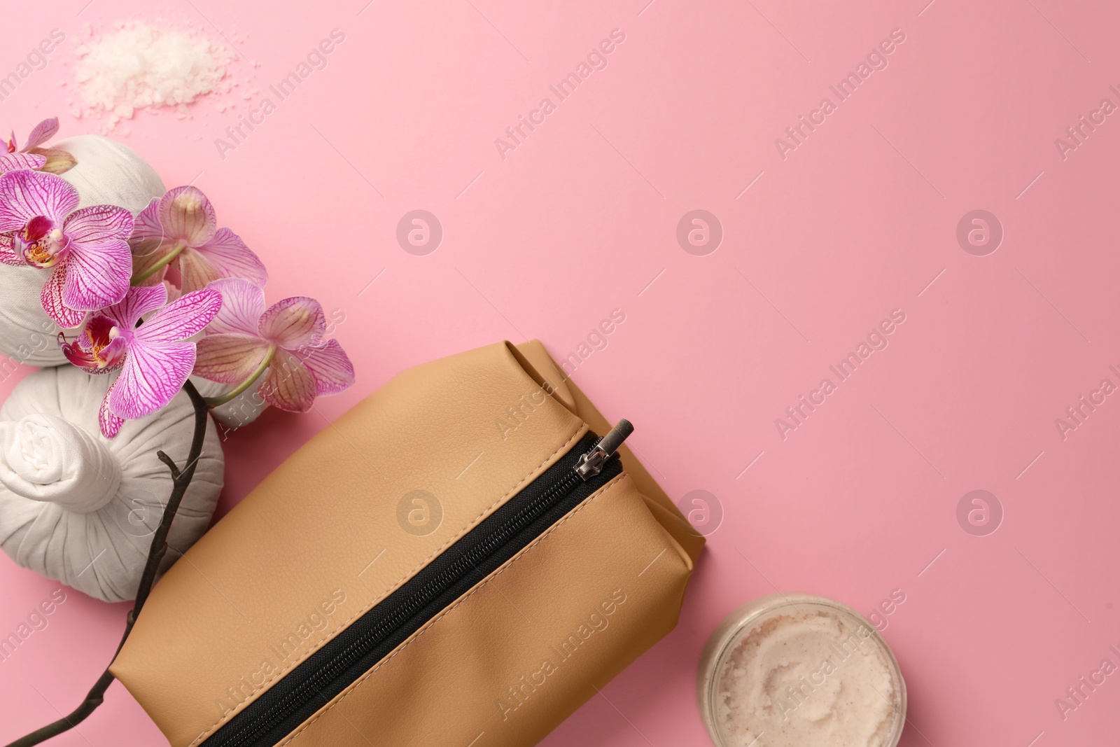 Photo of Preparation for spa. Compact toiletry bag, herbal bags and orchid on pink background, flat lay. Space for text