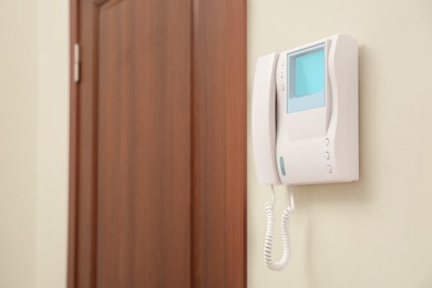 Modern intercom system with handset on white wall indoors, space for text