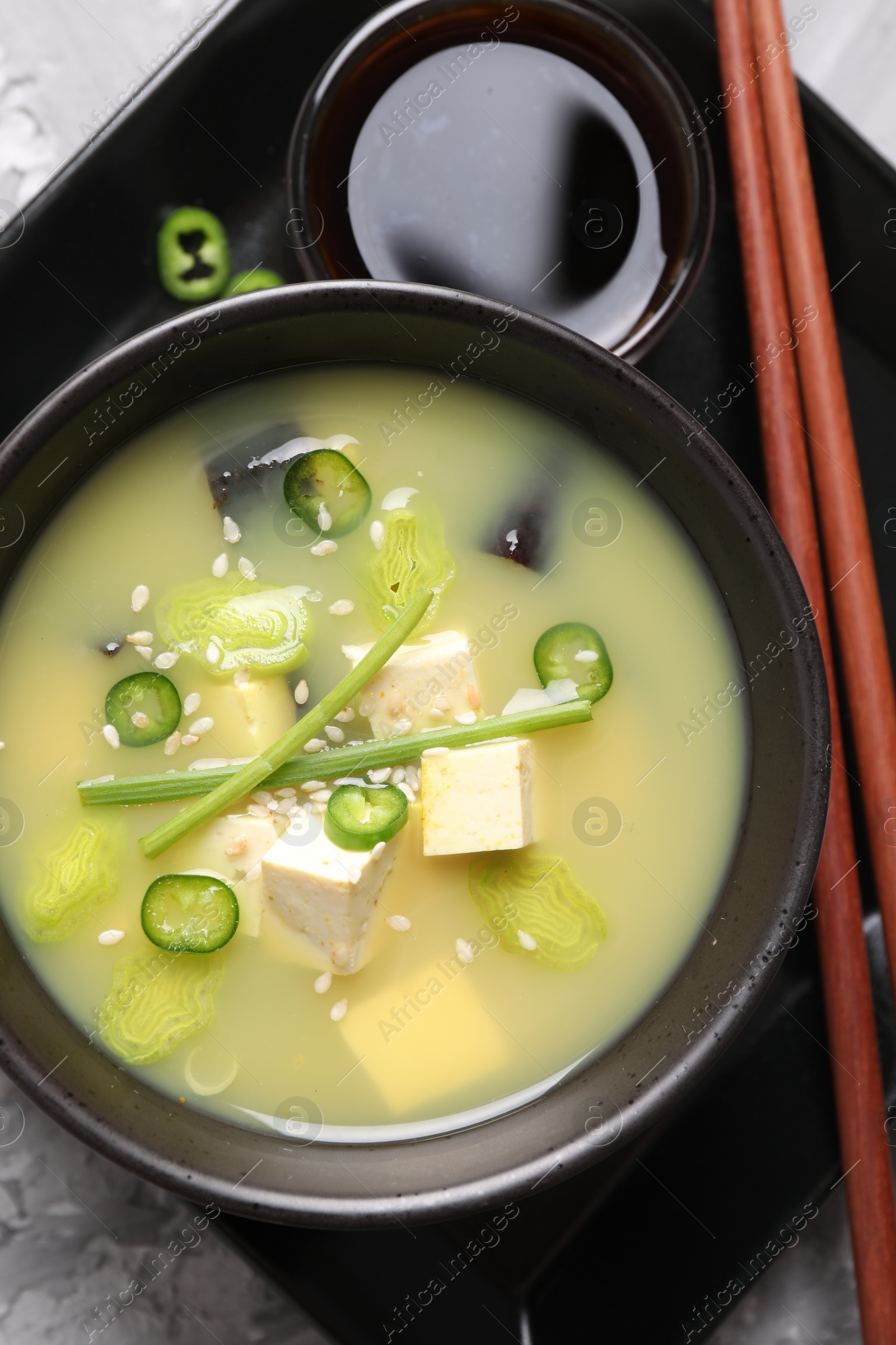 Photo of Bowl of delicious miso soup with tofu on table, top view