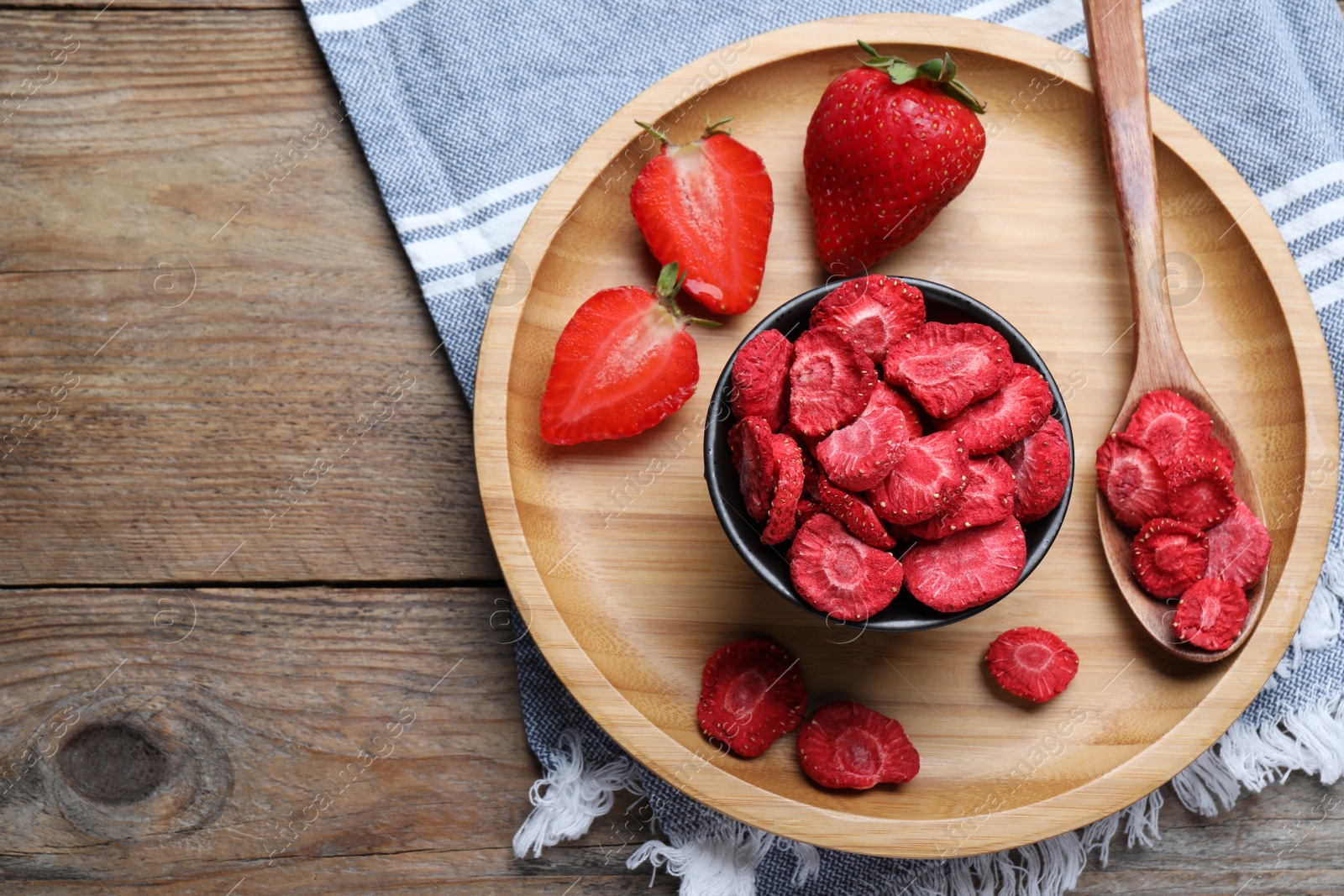 Photo of Freeze dried and fresh strawberries on wooden table, top view. Space for text