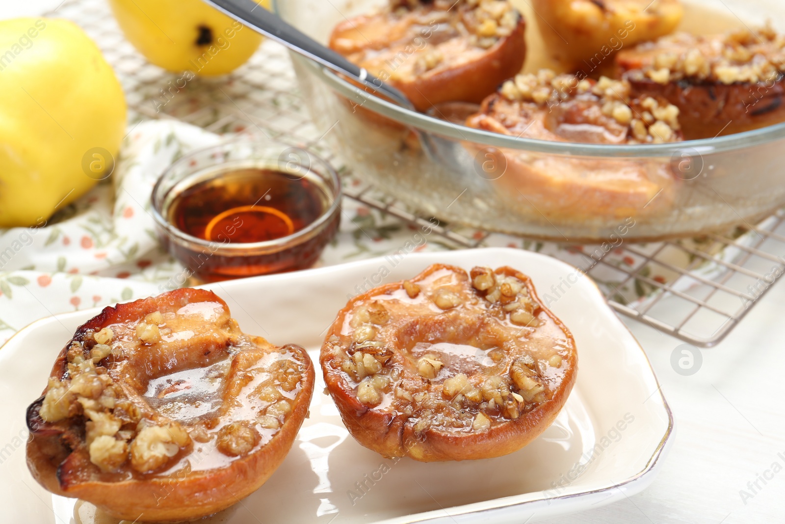 Photo of Delicious quinces baked with honey and walnuts on white table