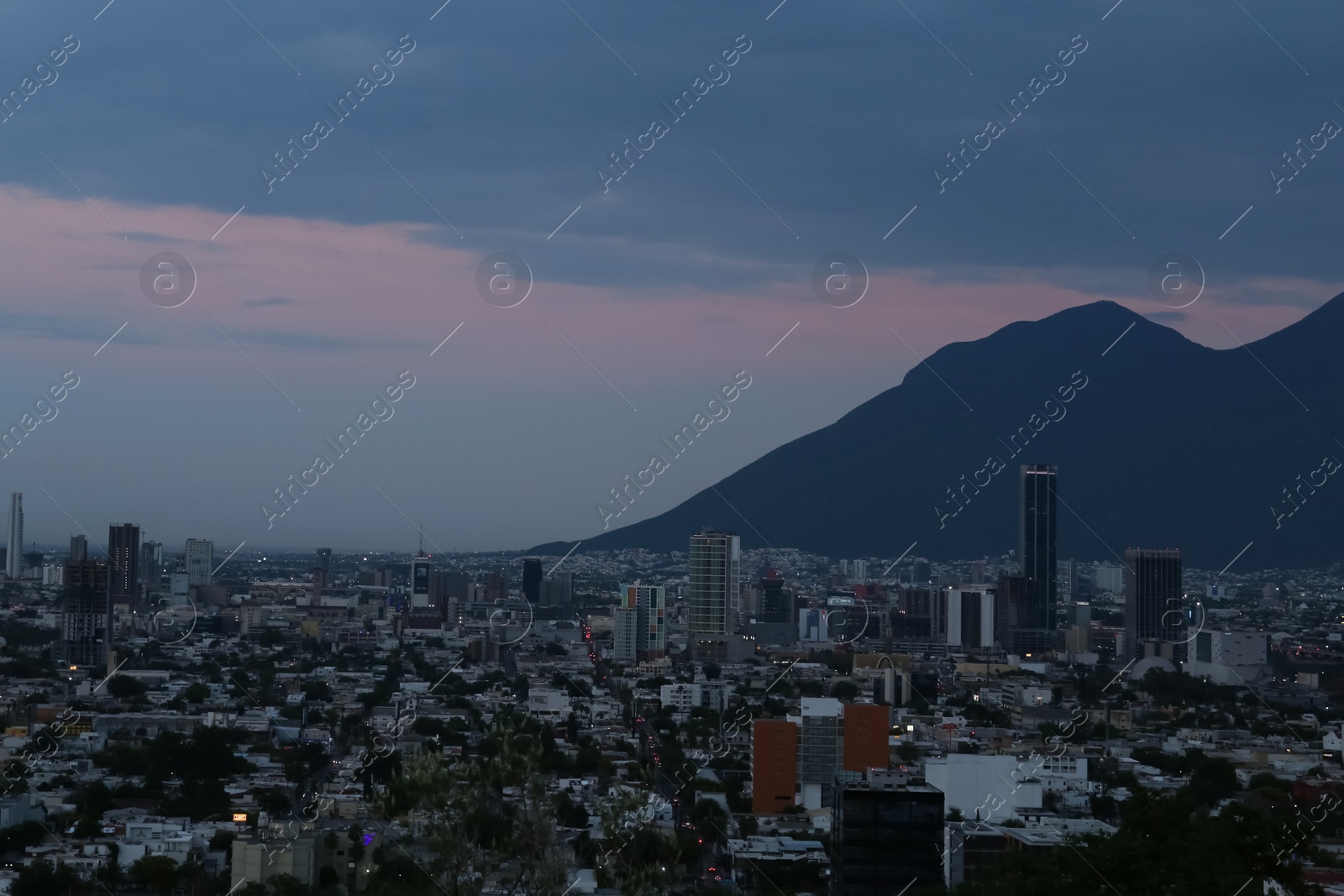 Photo of Picturesque view of sunset above big mountains and city