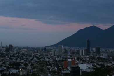 Photo of Picturesque view of sunset above big mountains and city