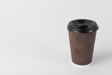 Photo of Brown paper cup with plastic lid on light background, space for text. Coffee to go