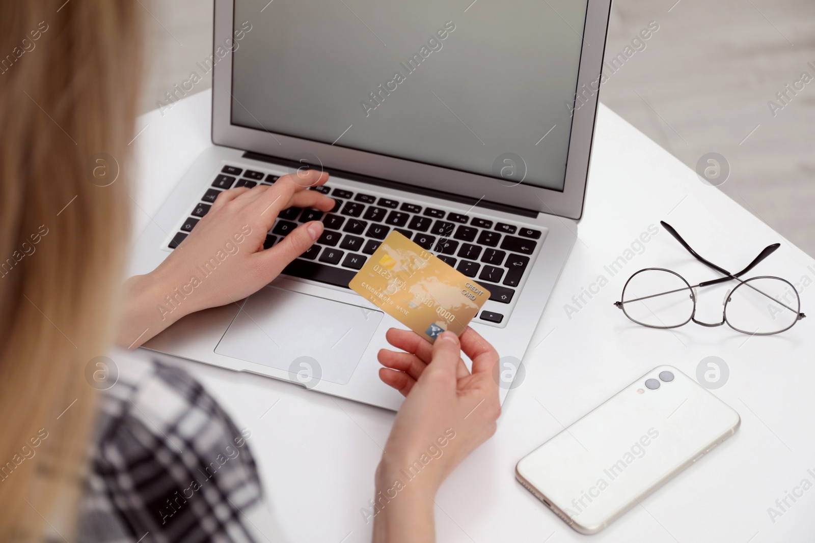 Photo of Woman with credit card using laptop for online shopping at white table, closeup