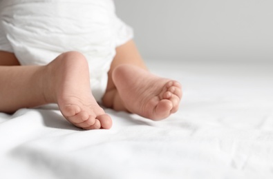 Photo of Cute little baby crawling on white bed sheet, closeup. Space for text
