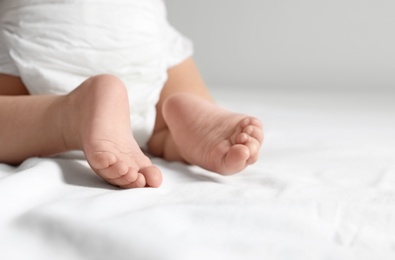 Cute little baby crawling on white bed sheet, closeup. Space for text