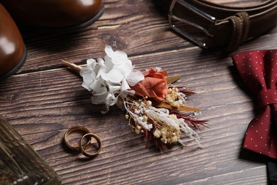 Photo of Wedding stuff. Composition with stylish boutonniere on wooden background, closeup