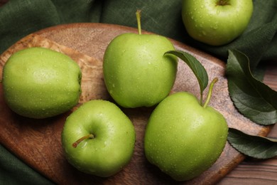 Photo of Ripe green apples with leaves and water drops on wooden table, flat lay