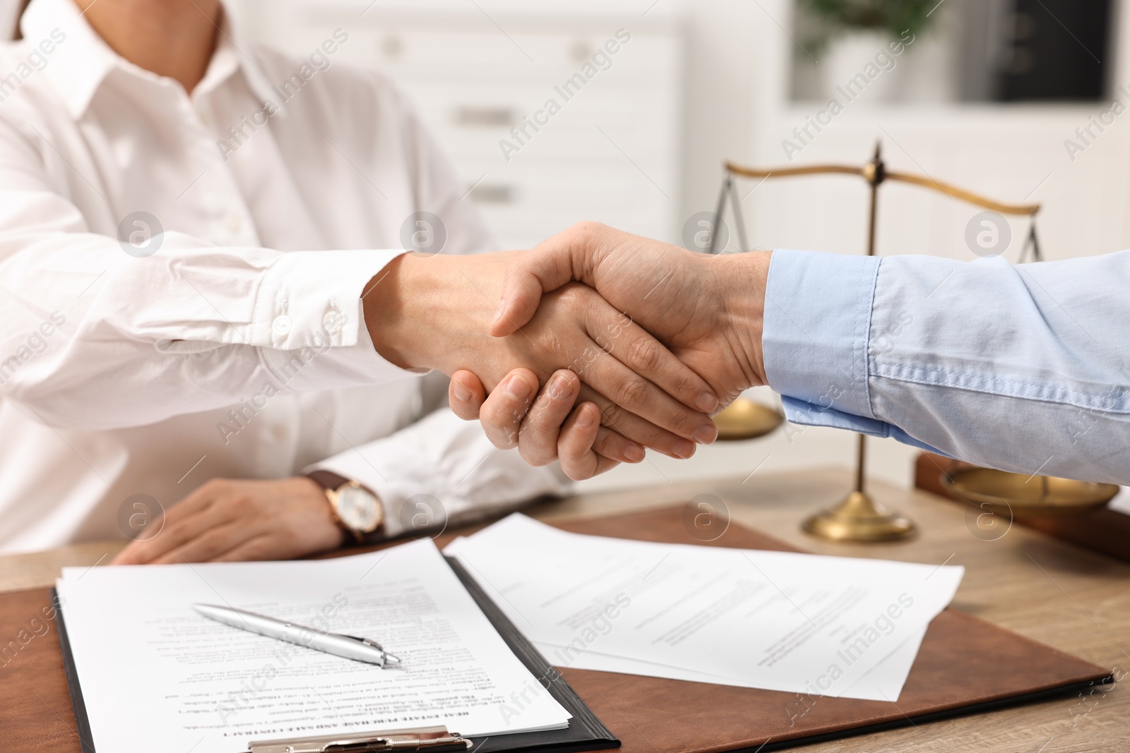 Photo of Lawyers shaking hands at table in office, closeup