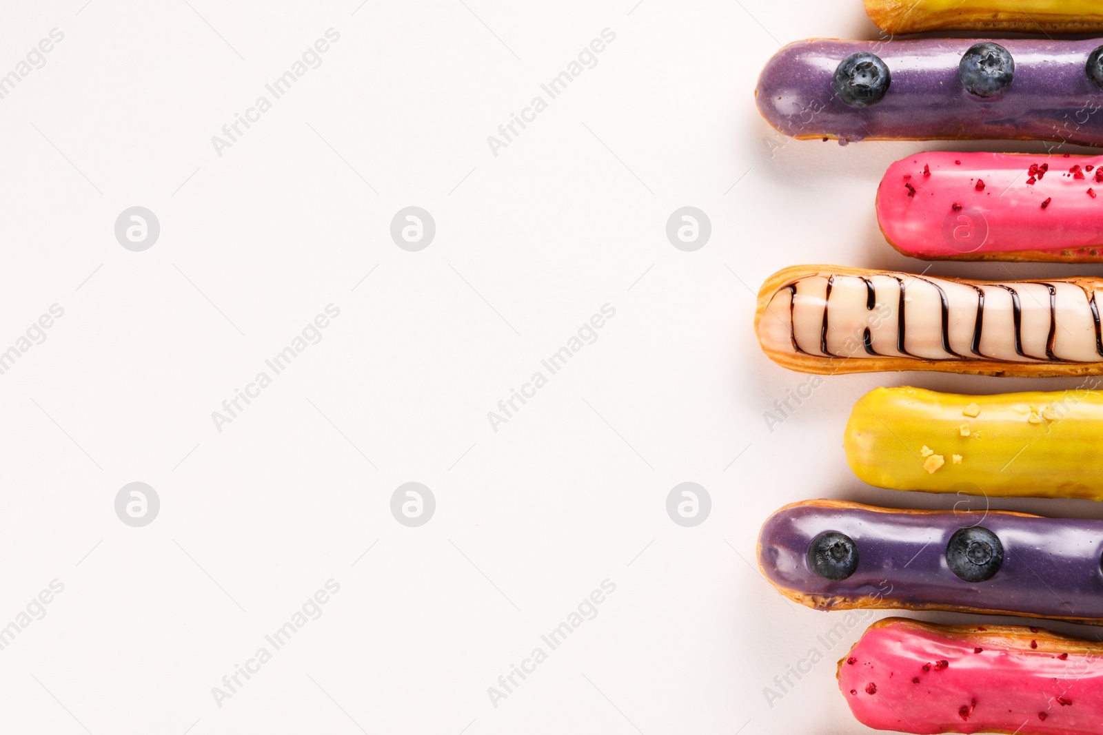 Photo of Delicious eclairs covered with glaze on white background, top view