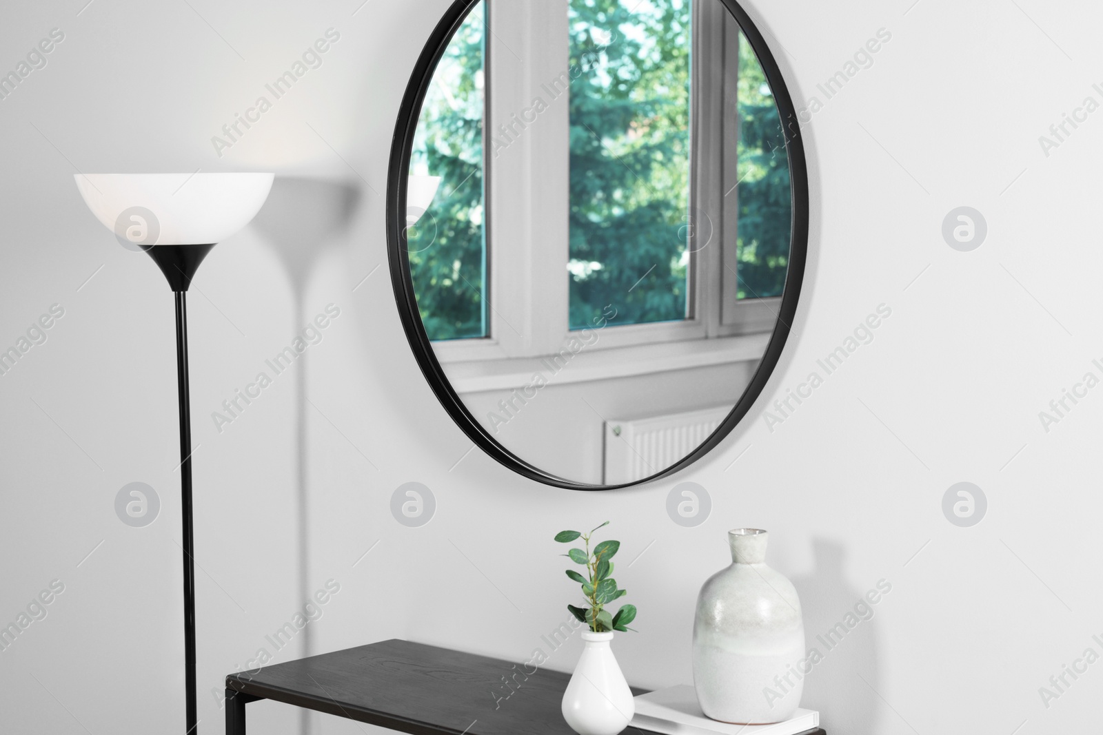 Photo of Stylish round mirror on white wall over table in room