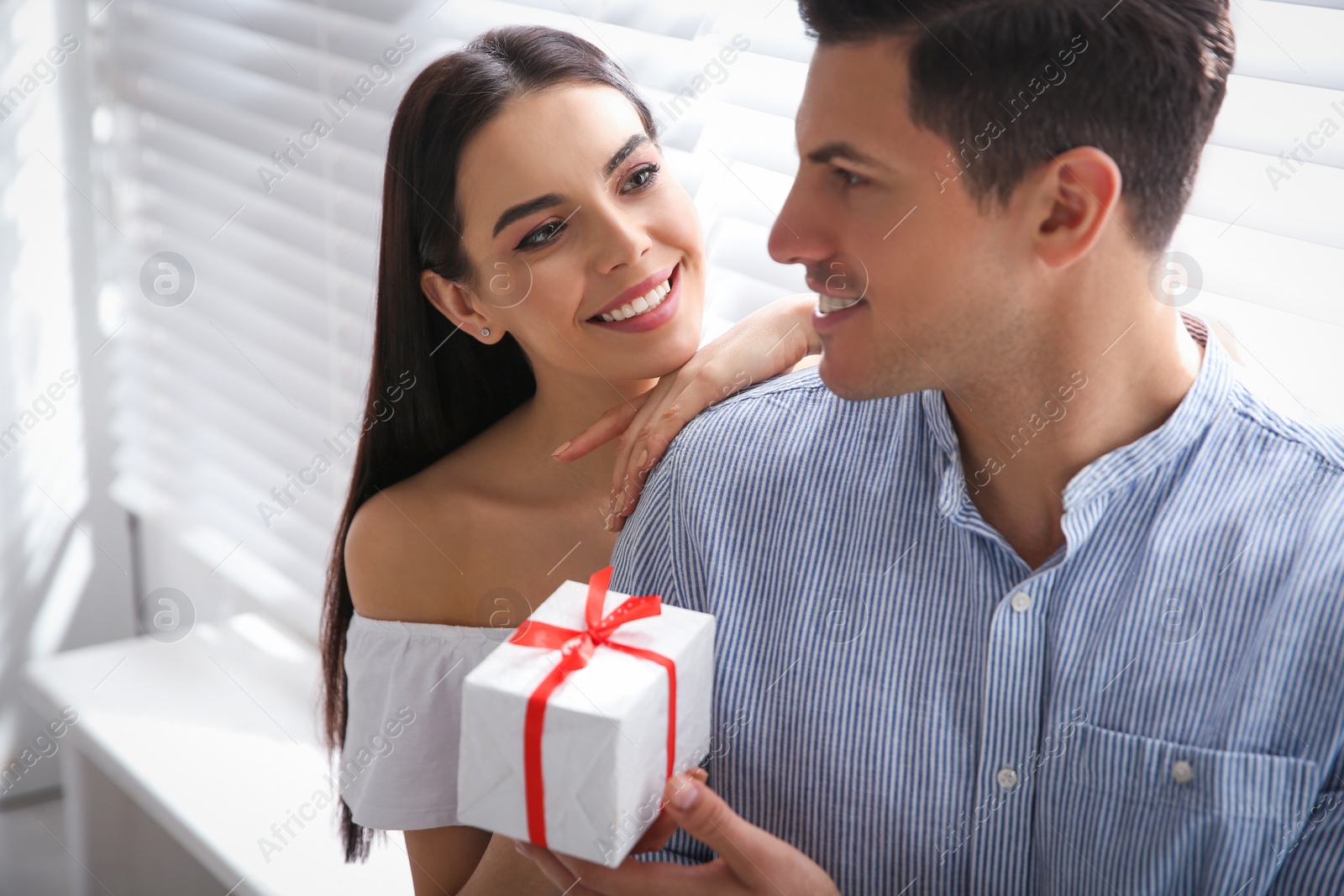 Photo of Lovely couple with gift box at home. Valentine's day celebration