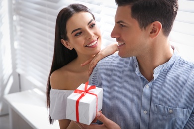 Lovely couple with gift box at home. Valentine's day celebration