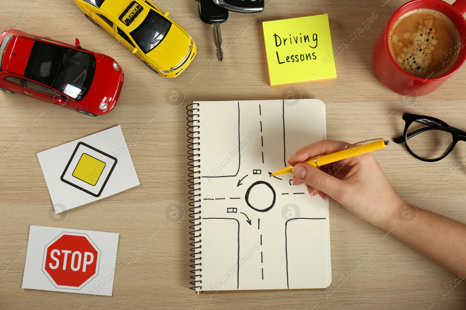 Photo of Woman with workbook for driving lessons and road signs at wooden table, top view. Passing license exam