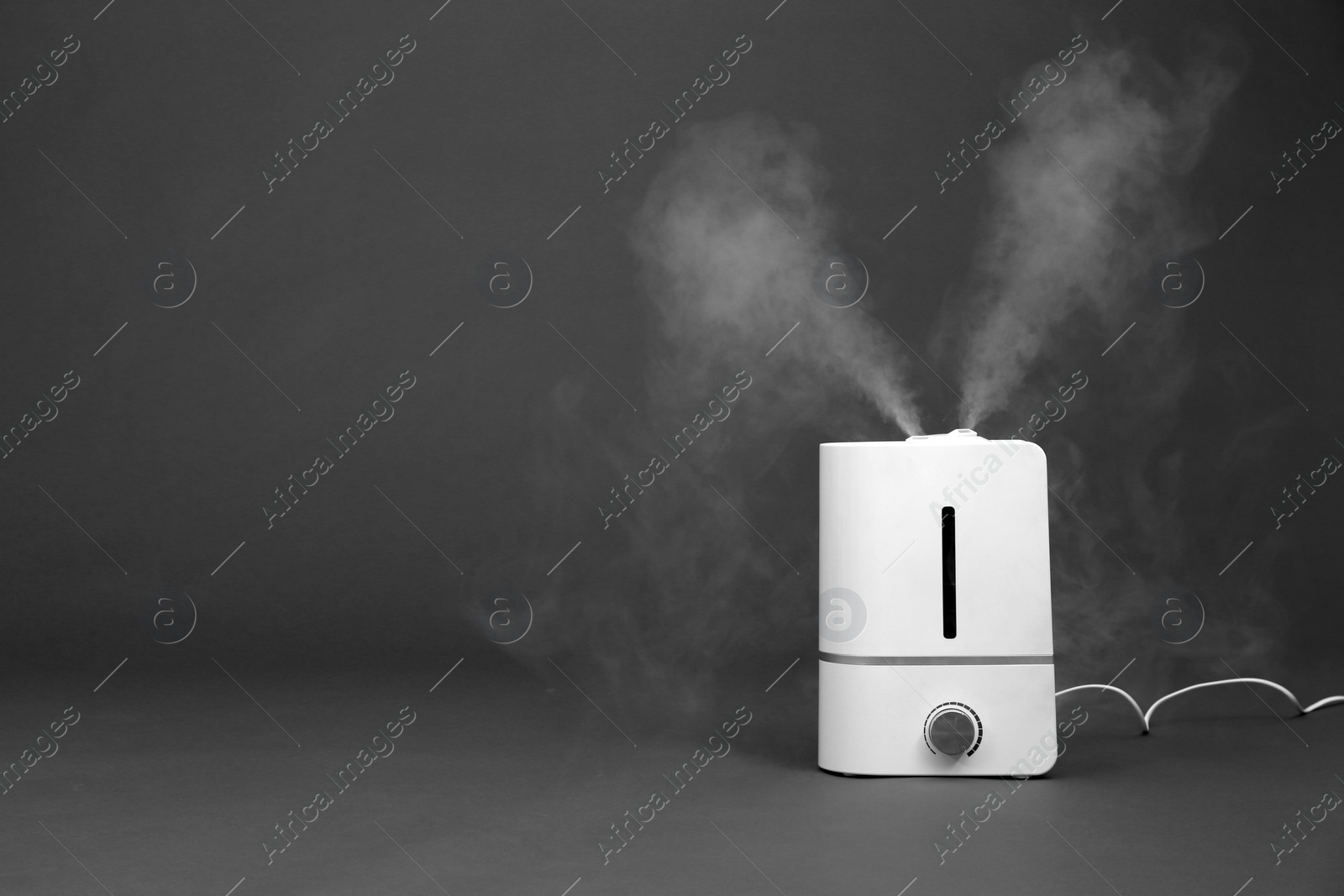 Photo of Modern air humidifier on grey background. Space for text