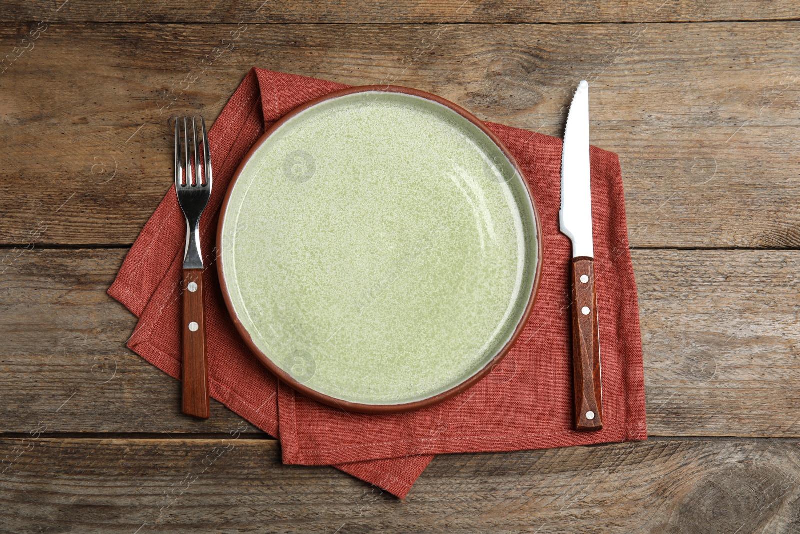 Photo of Empty plate, cutlery and napkin on wooden table, flat lay