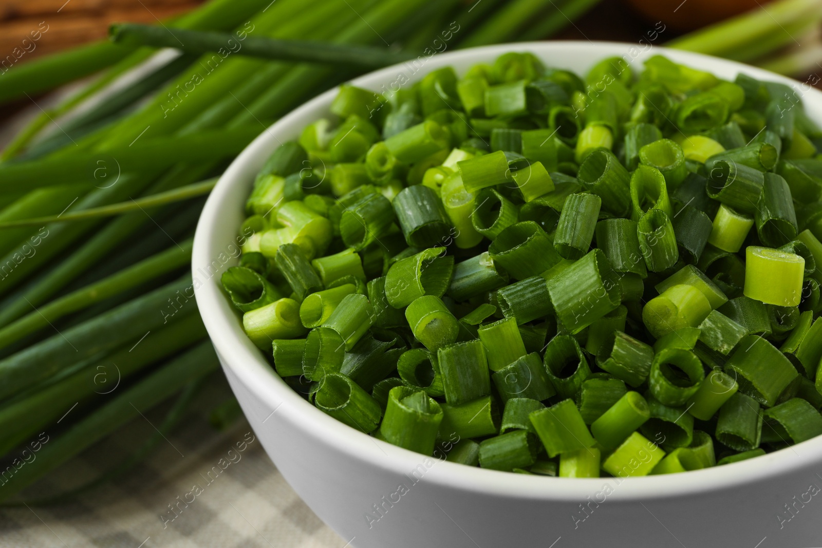 Photo of Chopped fresh green onion in bowl, closeup