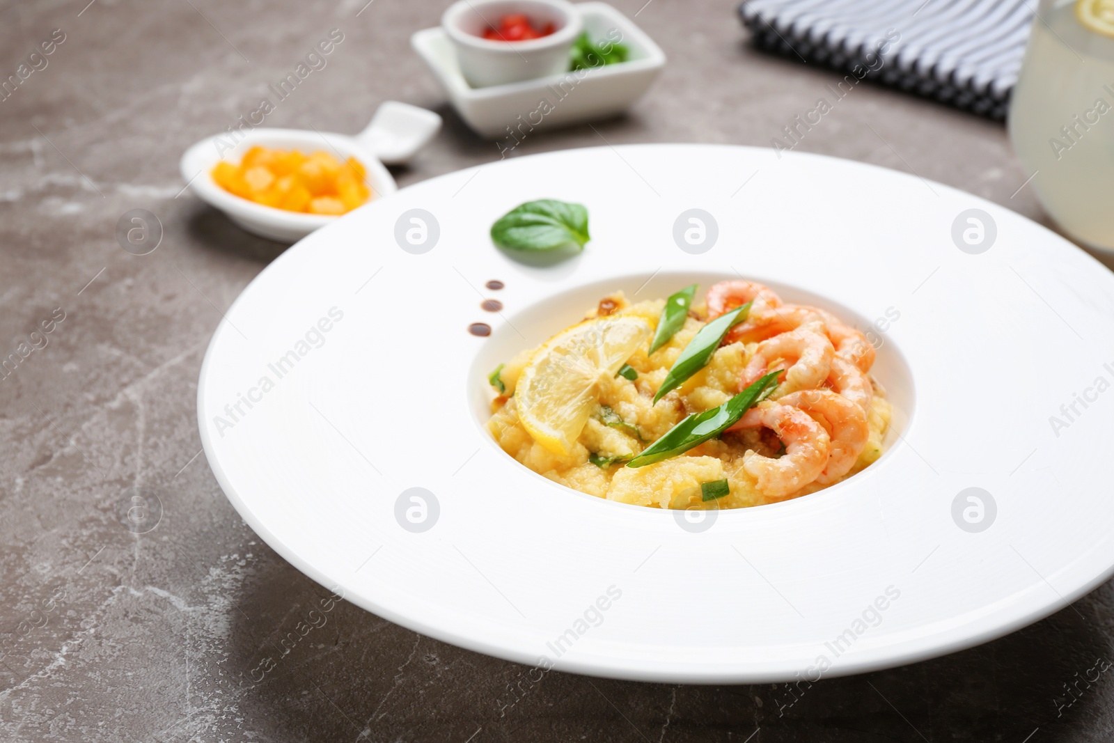 Photo of Plate with tasty shrimps and grits on table