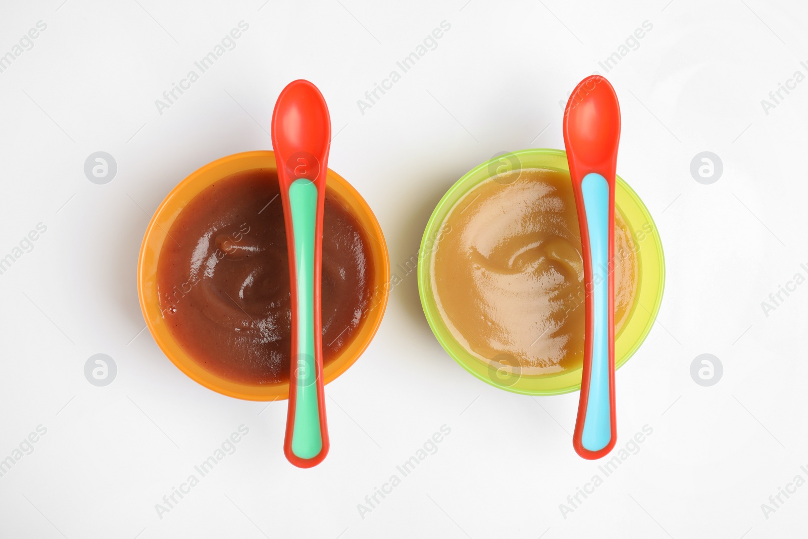 Photo of Bowls with healthy baby food and spoons on white background, flat lay