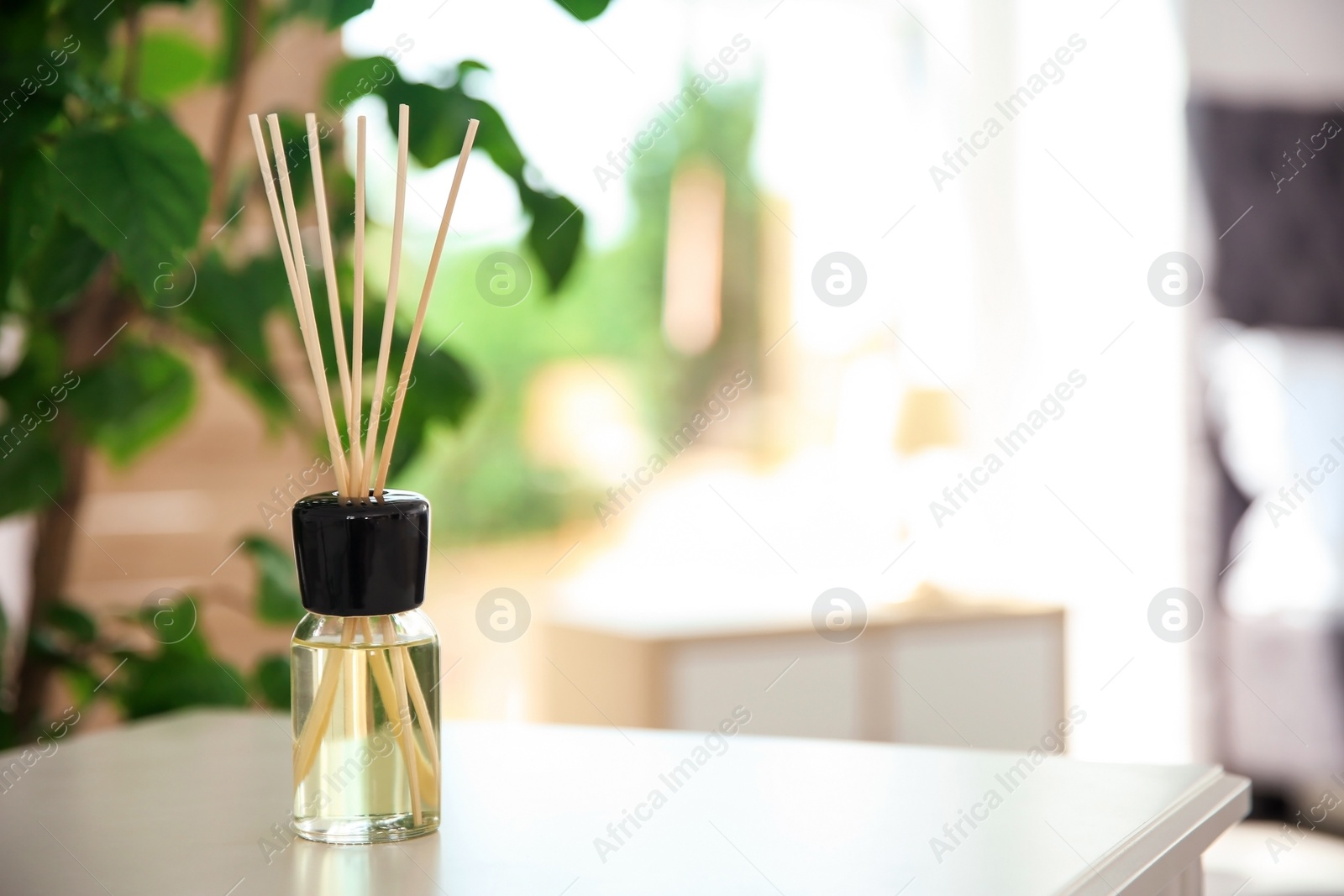 Photo of Aromatic reed air freshener on table indoors