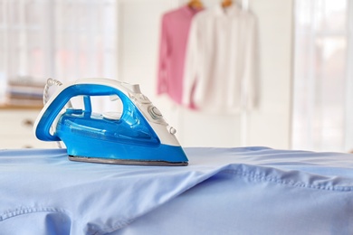 Photo of Clean shirt and iron on board indoors