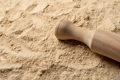 Photo of Heap of buckwheat flour and rolling pin, closeup. Space for text
