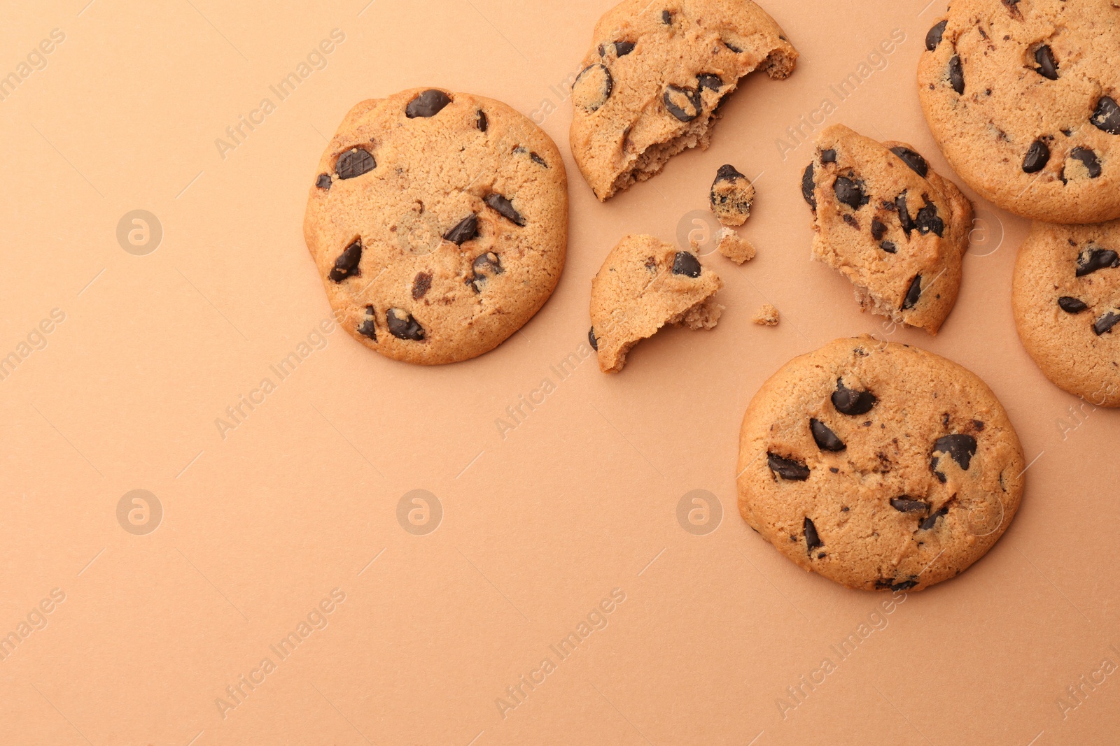 Photo of Many delicious chocolate chip cookies on beige background, flat lay. Space for text