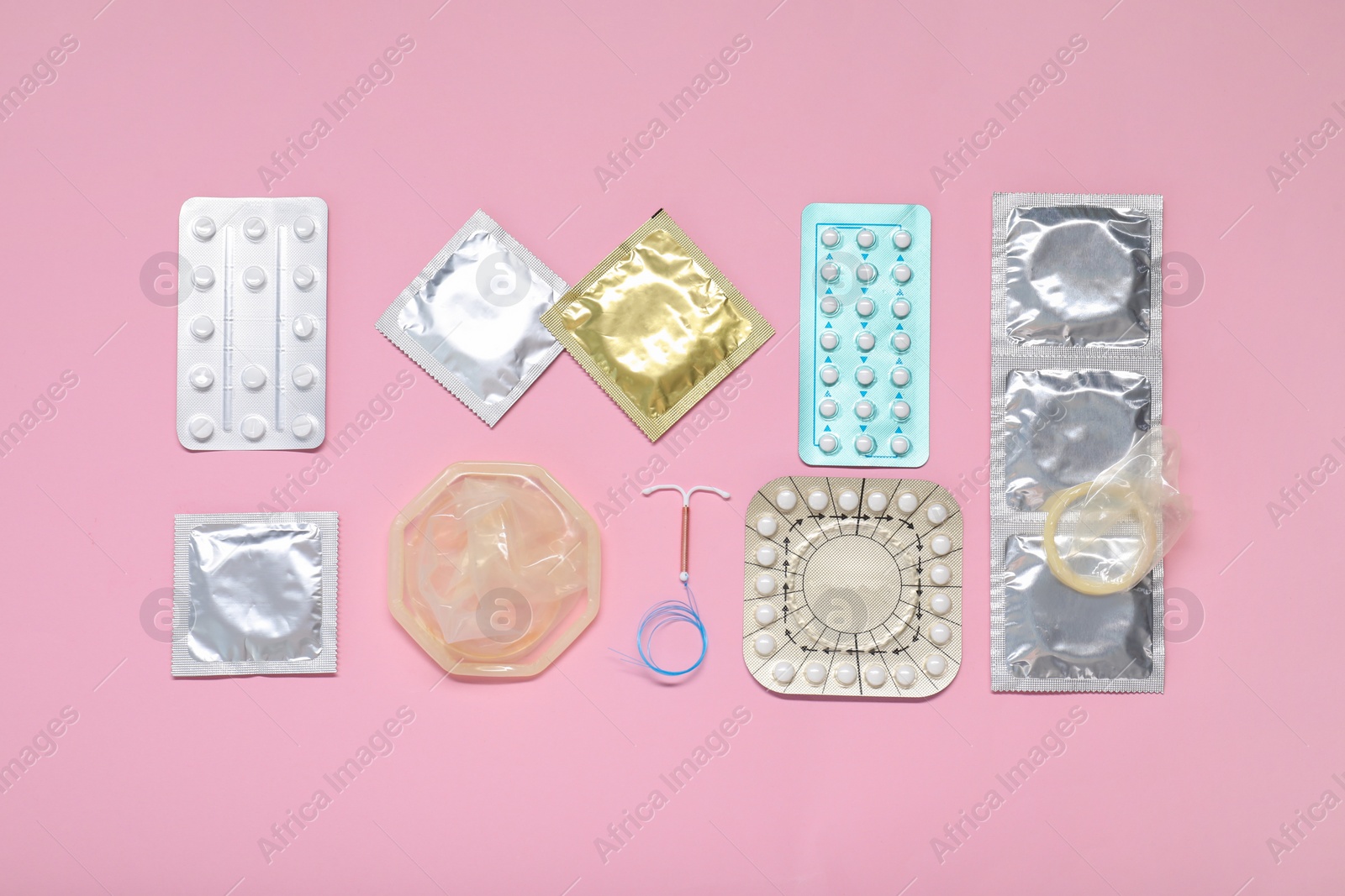 Photo of Contraceptive pills, condoms and intrauterine device on pink background, flat lay. Different birth control methods