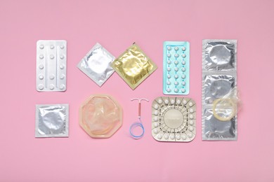 Photo of Contraceptive pills, condoms and intrauterine device on pink background, flat lay. Different birth control methods