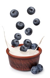 Image of Delicious ripe blueberries falling into bowl with yogurt on white background