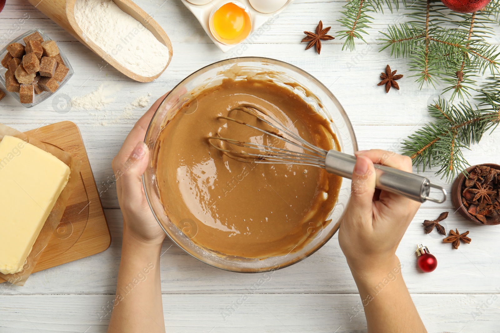 Photo of Woman cooking traditional Christmas cake at white wooden table with ingredients, top view