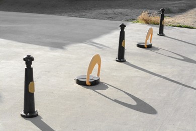 Photo of Parking barriers with No Stopping road sign and poles on asphalt outdoors
