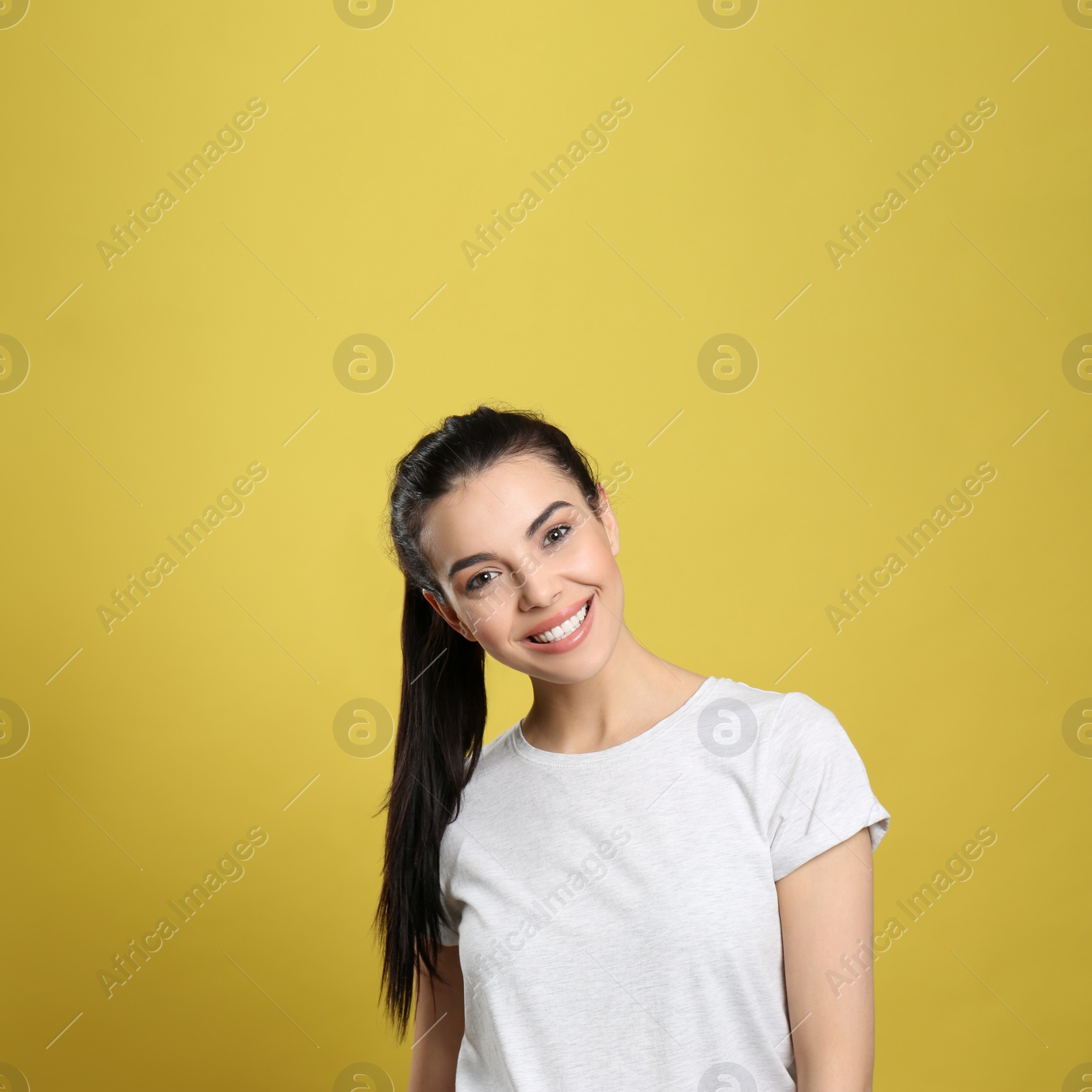 Photo of Portrait of happy young woman with beautiful black hair and charming smile on yellow background, space for text