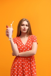 Young woman with glass of delicious milk shake on color background